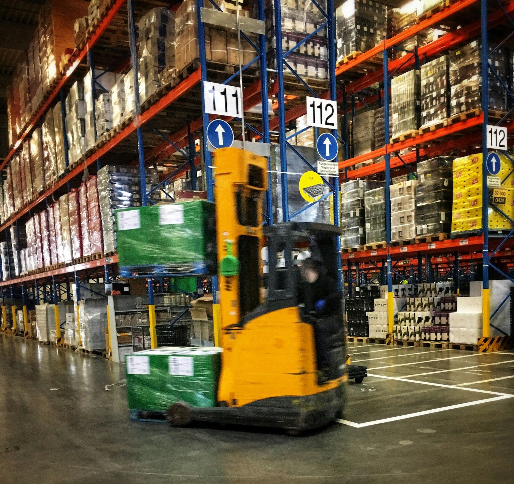 Forklift moving pallets through a busy warehouse