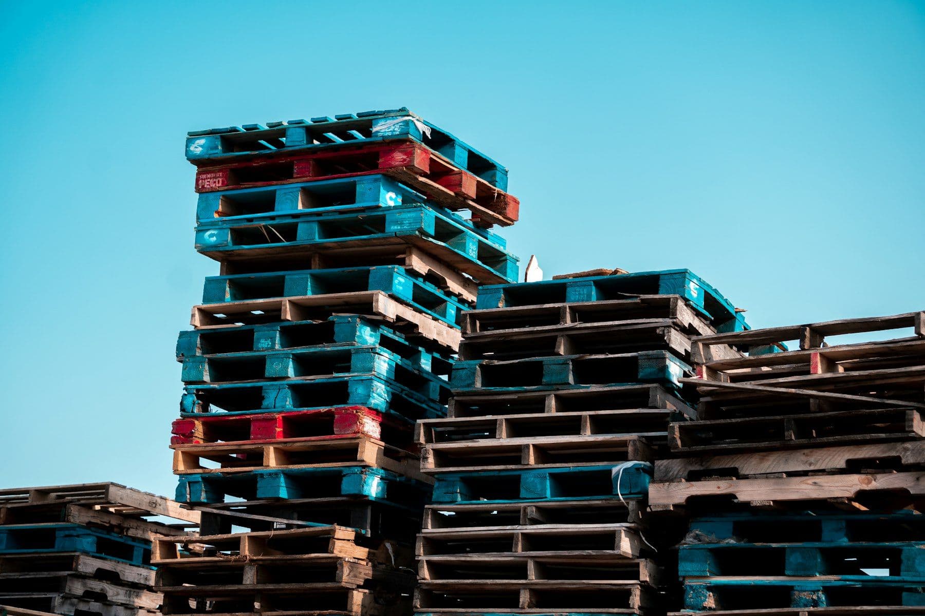 Stacked wooden pallets against a blue sky