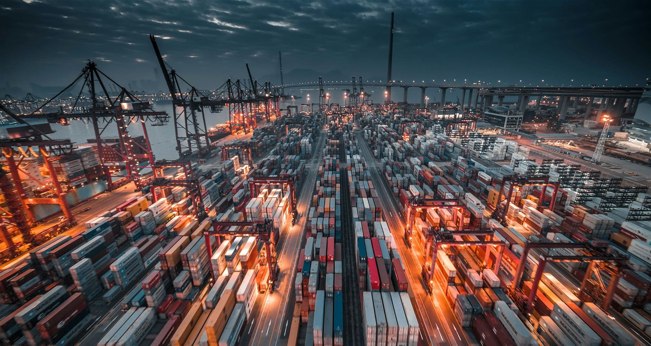 Container port at dusk with cranes and stacked containers